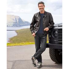 Grey-Denim-Jeans Mann in schwarzer Lederjacke vor Geländewagen in der Natur.