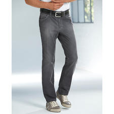 Grey-Denim-Jeans Mann in grauen Denim-Jeans und T-Shirt steht vor einem Fenster.