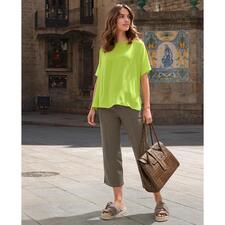 Limette Frau in greller grüner T-Shirt-Bluse und grauen Hose auf der Straße.