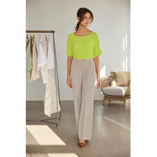 Limette Frau in einer leuchtend gelben T-Shirt-Bluse, neben einem Kleiderständer.