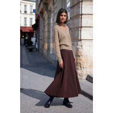 Raccoon-Flausch-Pullover Frau in braunem Flausch-Pullover und Maxiröcken auf einer Straße.