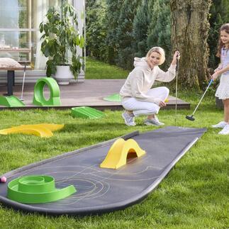Frau mit Kind spielt Minigolf auf einem mitgenommenen Minigolfplatz.