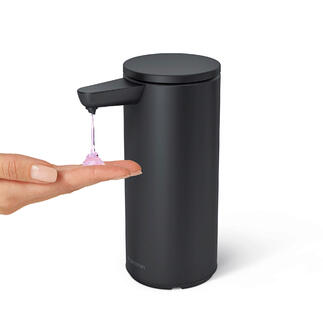 Schwarzer Sensor-Seifenspender gibt Seife auf eine Hand.