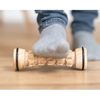 Fußmassage-Roller aus Holz, ein Fuß liegt darauf.