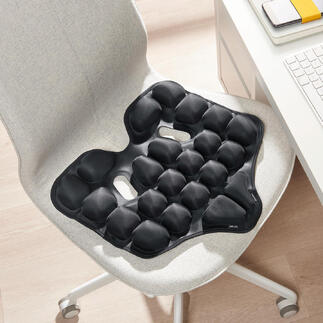Schwarzes ergonomisches Sitzkissen auf einem Stuhl.