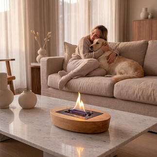 Moderner Eiche-Tischkamin mit Flamme, Frau entspannt neben einem Hund auf der Couch.