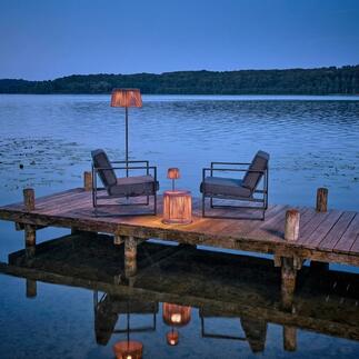 Outdoor-Tisch mit LED-Beleuchtung am Wasser, umgeben von Stühlen.