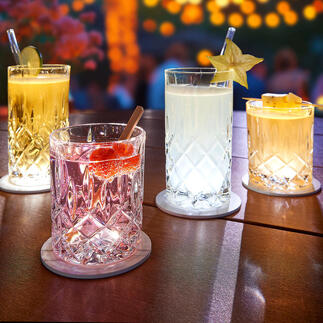 Vier beleuchtete Gläser auf einem Tisch mit LED-Untersetzer, ideal für eine festliche Atmosphäre.
