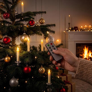 Hand, die eine Fernbedienung für LED Echtwachs-Christbaumkerzen am Weihnachtsbaum hält.