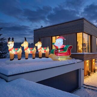 Aufblasbarer Rentierschlitten mit Santa Claus auf dem Dach eines modernen Hauses.