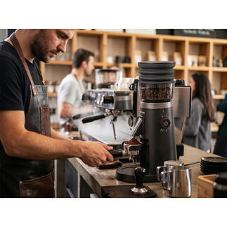 Barista mahlt Kaffeebohnen mit elektrischer Kaffeemühle im Café.