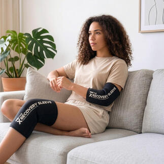 Model sitzt auf dem Sofa mit schwarzer Kälte-/Wärme-Bandage am Knie