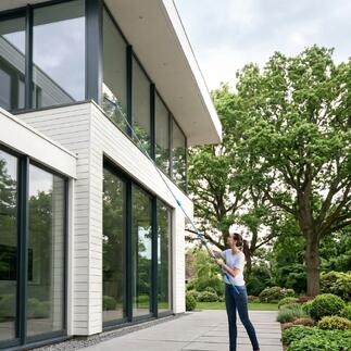 Frau reinigt Fenster mit Glas-Oberflächen-Cleaning-Set