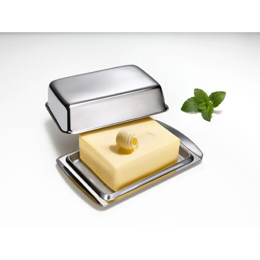 Edelstahl-Butterdose mit Deckel und Stück Butter auf einer weißen Unterlage