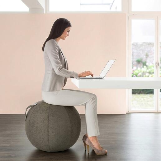 Frau sitzt auf einem Sitzball am Schreibtisch
