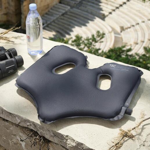 Bequemer SoftAirSeat auf einem Stein mit Wasserflasche und Fernglas.