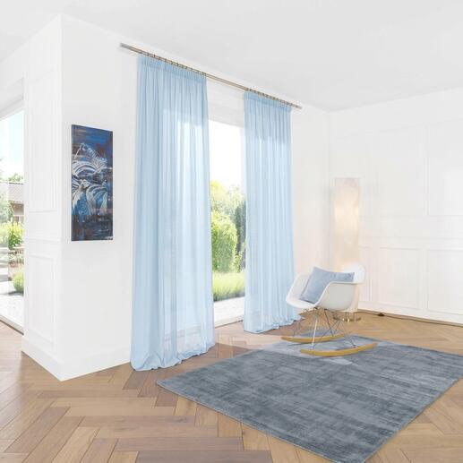 Hellblauer Vorhang, sanft fallend im Zimmer mit moderner Einrichtung.