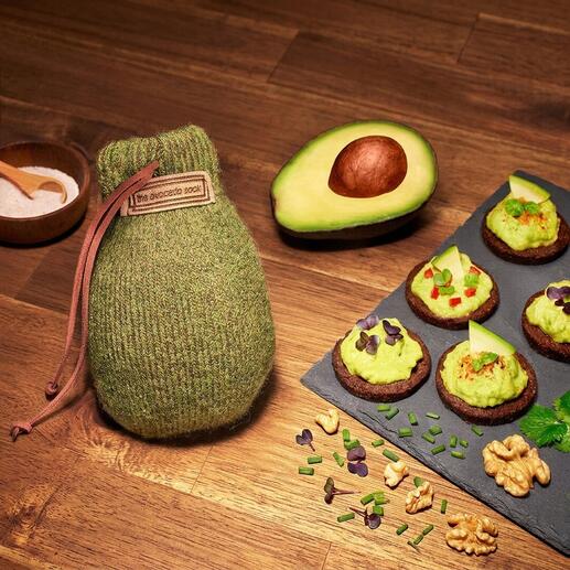 Avocado Sock® zusammen mit Avocado und Snacks auf einem Holztisch.