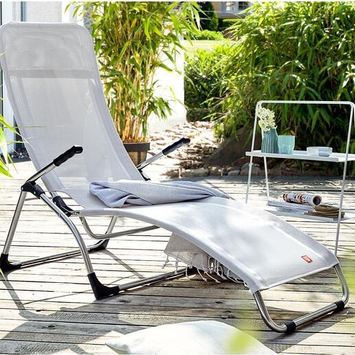 Klappbare Sitzliege steht auf einer Terrasse, umgeben von Pflanzen.
