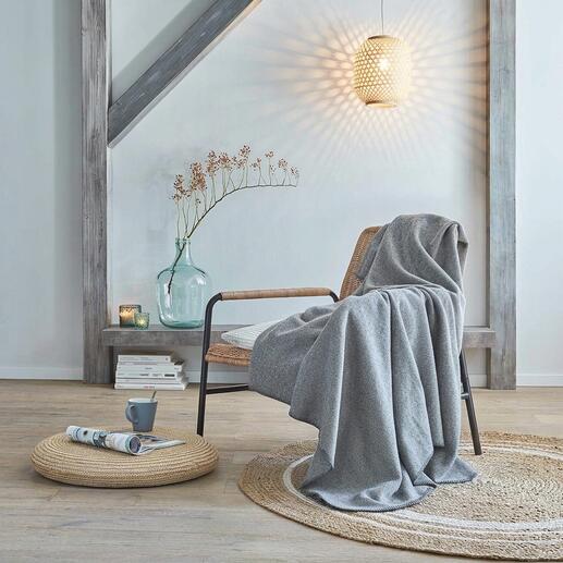 Woll-Fleecedecke auf einem Stuhl in einem modernen Wohnraum.