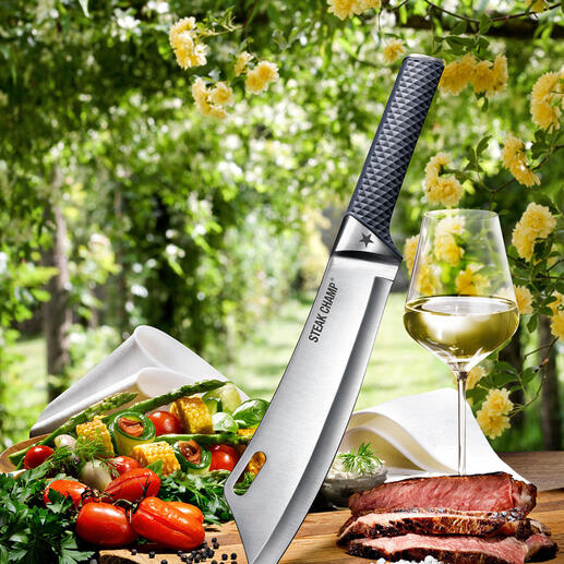 SteakChamp Kochmesser von oben, umgeben von Gemüse und Fleisch auf einem Holzbrett.