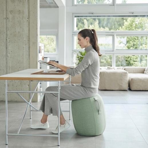 Frau sitzt auf einem luftgefüllten Balance-Hocker und arbeitet am Laptop