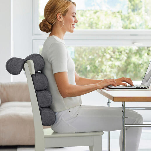 Frau sitzt mit Flexi-Rollenkissen am Schreibtisch und arbeitet am Laptop.