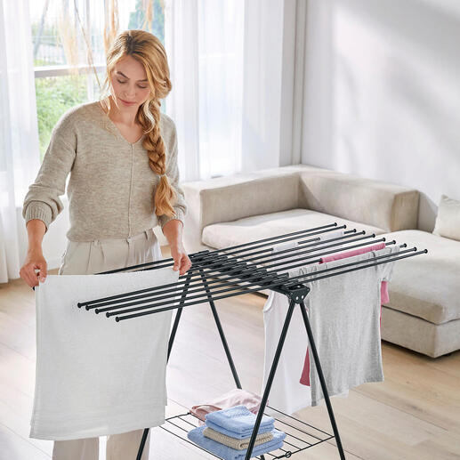 Frau organisiert Wäsche auf einem Design-Wäscheständer im Wohnraum