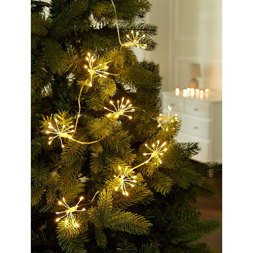 Lichterkette mit goldenen Lichtern, die wie Wunderkerzen auf einem Weihnachtsbaum wirken.