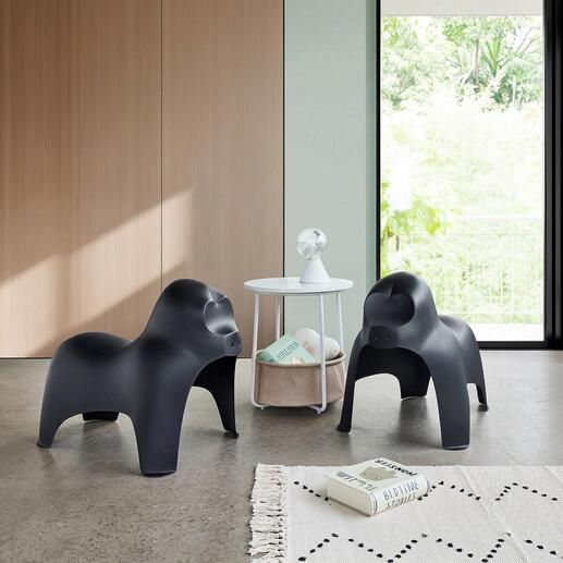 Zwei schwarze Gorilla-Hocker stehen in modernem Wohnraum mit Tisch.
