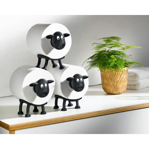 Drei Toilettenpapierhalter in Form von Schafen auf einem Tisch.