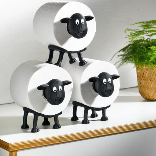 Drei Toilettenpapierhalter in Form von Schafen auf einem Tisch.