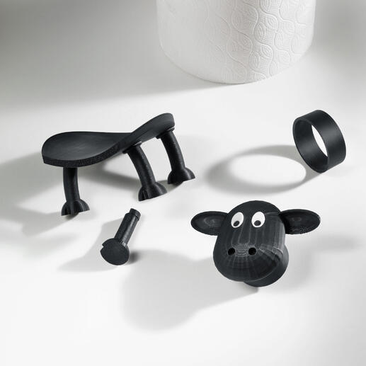 Komplett im 3D-Druckverfahren in Deutschland hergestellt. Zerteilte Teile eines Toilettenpapierhalters in Schaf-Design auf einem Tisch.