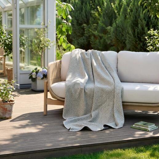 Umkehrbare jacquard Decke liegt auf einer Gartenbank.