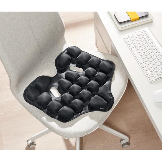 Schwarzes ergonomisches Sitzkissen auf einem Stuhl.