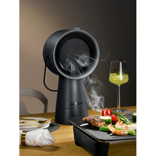 Airhood 2.0 in Schwarz, dampfendes Grillgerät auf Tisch mit Gemüse und Fleisch.