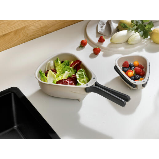 Platzsparendes Küchensieb mit frischem Gemüse und Obst im Hintergrund.