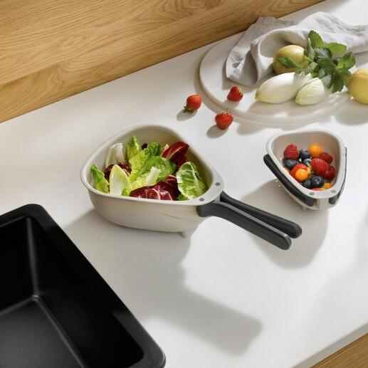 Platzsparendes Küchensieb mit frischem Gemüse und Obst im Hintergrund.