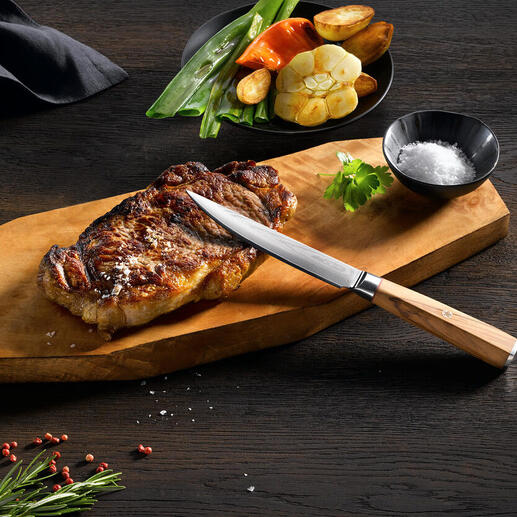 Damast-Steakmesser auf Holzbrett mit gegrilltem Steak und Gemüse.