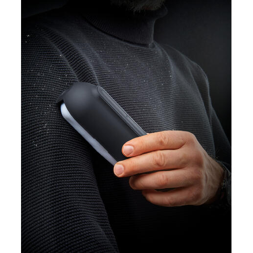 Ultraklebender Fusselroller in der Hand eines Mannes, mit Fusseln auf einem Pullover.