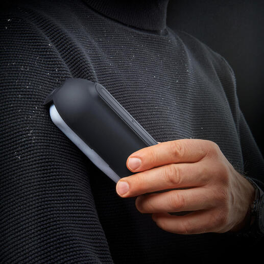 Ultraklebender Fusselroller in der Hand eines Mannes, mit Fusseln auf einem Pullover.