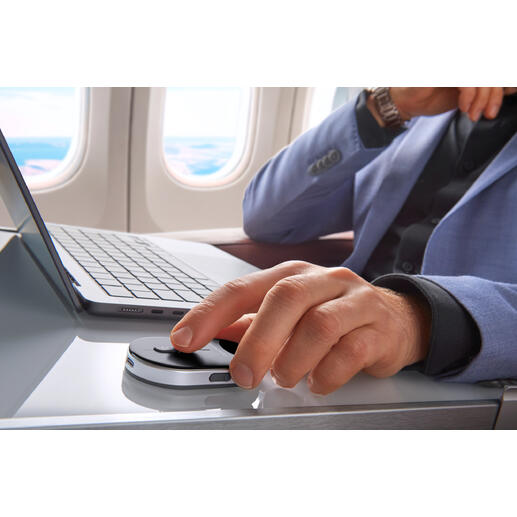 Mann in einem Flugzeug nutzt eine mobile Mini-Maus auf einem Tisch.