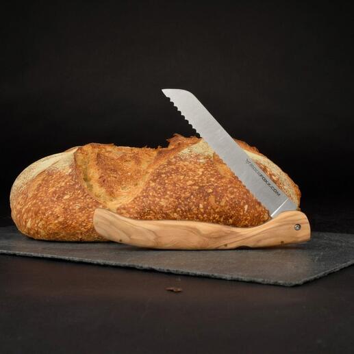 Klappbares Brotmesser mit Olivenholzgriff neben einem Laib Brot auf einer schwarzen Unterlage.