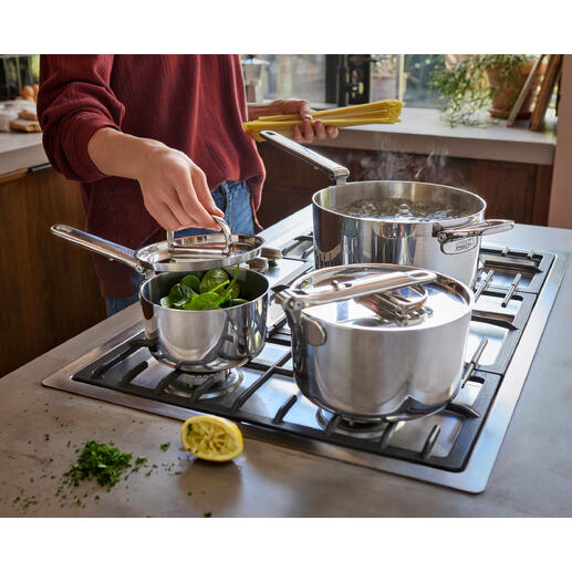 Kochgeschirr-Set mit Klappgriff, eine Pfanne und zwei Töpfe mit Gemüse auf dem Herd.