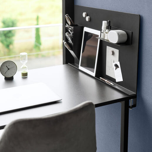 Schwarze magnetische Pinnwand mit Büroaccessoires auf einem Schreibtisch.