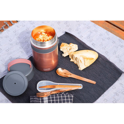 Isolierende Snackbox in Rosé mit geöffnetem Deckel, neben Brot und Besteck auf einer Decke.