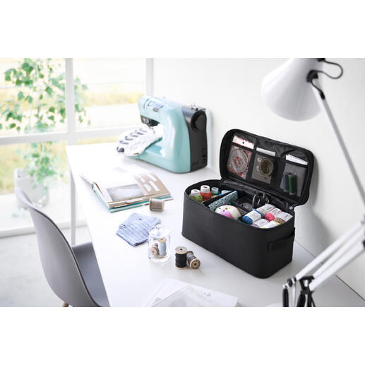 Kleinere Werkzeugbox in Hellgrau mit verschiedenen Fächern, auf einem Tisch.