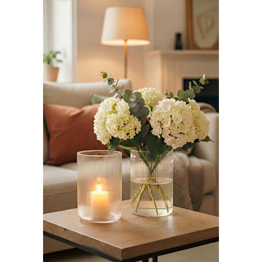 Zwei Vasen mit weißen Blumen und Licht in einem modernen Wohnraum.