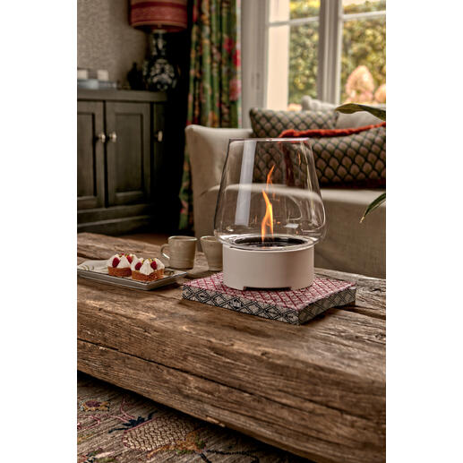 Tischfeuer in einem modernen Glasbehälter auf einem Holztisch.
