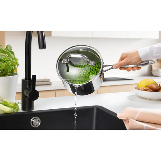 Stielkasserolle mit Siebdeckel, Wasser wird in die Spüle gegossen.